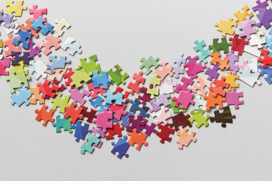 Overhead shot of scattered white puzzle pieces on a bright, clean surface, symbolizing the problem of data fragmentation i...